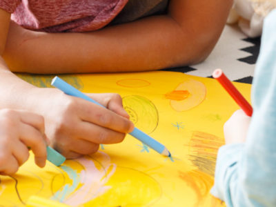 Little kids drawing pictures with crayons on yellow paper