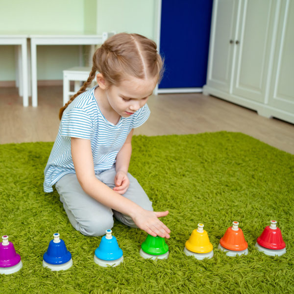 little girl playing with colourful musical bells.